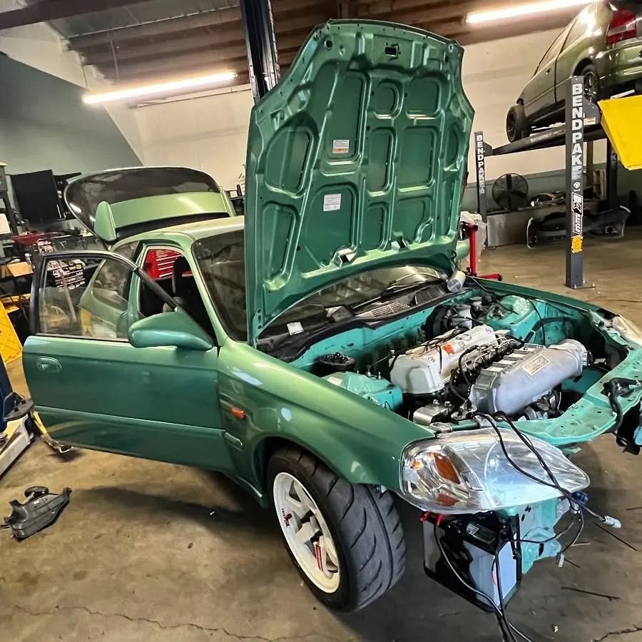 A green Honda Civic with its hood open inside the Spearmint Dyno shop